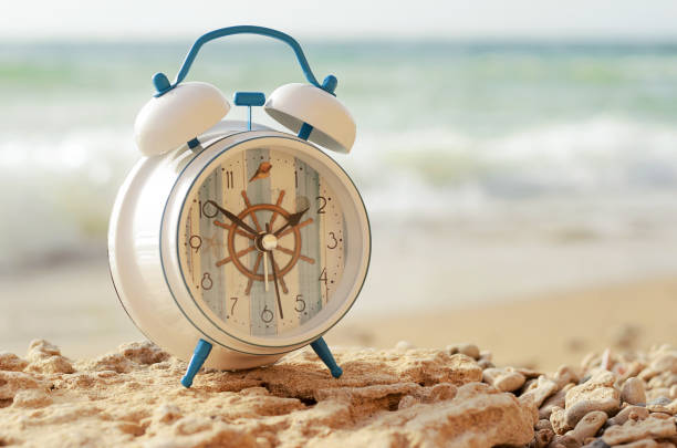 Summer Time Alarm clock on the Beach Vacation Travel Concept Daylight Saving Time Summer Time Beach Party Alarm clock on the Coast Vacation Travel Summertime Concept Copy Space Daylight Saving Time Vintage background for flyer, banner, brochure, invitation, poster bellcaptain stock pictures, royalty-free photos & images