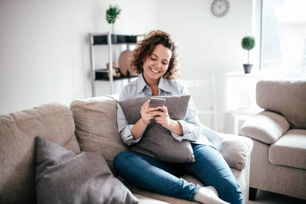 istock Woman uses cellphone on sofa at home 965668578