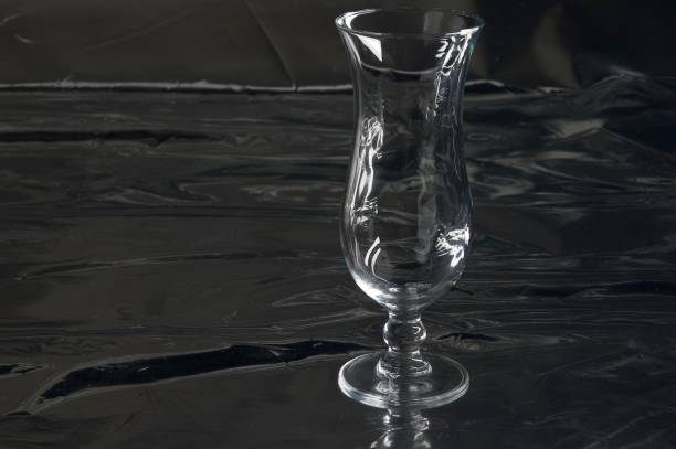 istock Still life with one empty single modern transparent and fragile (cocktail) glass on a table with a black background 965669212