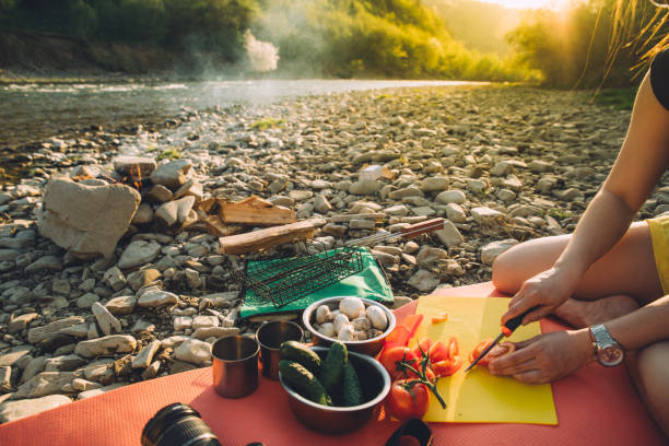 woman cooking on camp fire. wild nature resting. cutting tomatoes - strand imagens e fotografias de stock