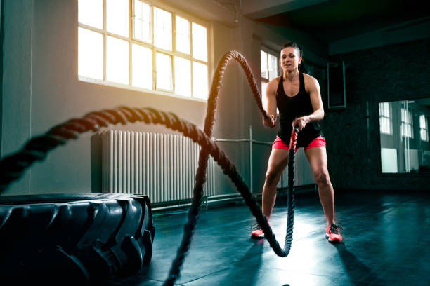 entrenar crossfit duro intenso con cuerda en el gimnasio - effort dark concepts women fotografías e imágenes de stock