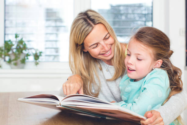 istock Girl With Mother Reading Book At Home 965674886