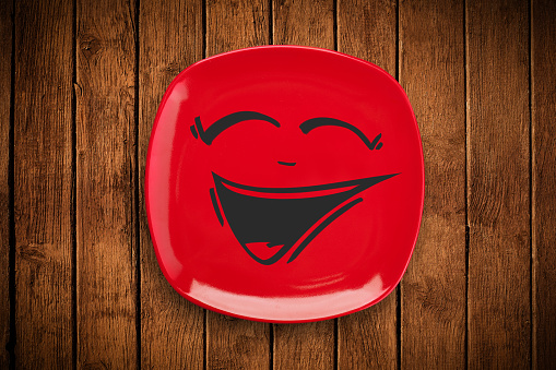 Happy smiley cartoon face on colorful dish plate and grungy background