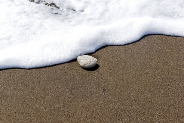 istock A lonely stone on the sand in the surf. 965695160