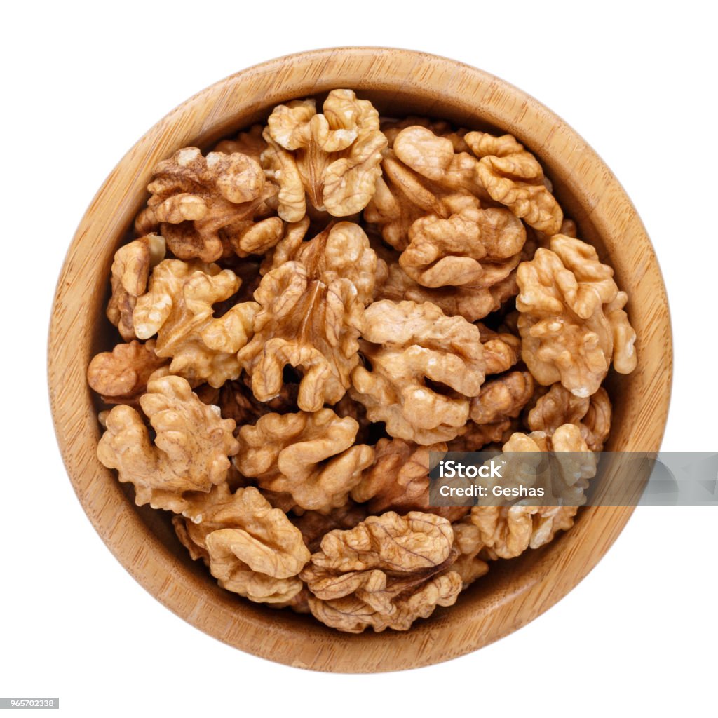 Peeled walnuts in wooden bowl isolated on white. Top view. Walnut Stock Photo