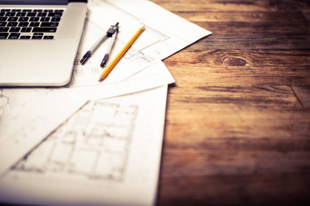 Laptop and architectural blueprints on a wooden desk