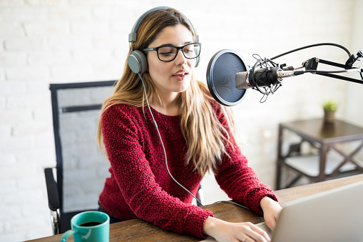 Portrait of attractive caucasian woman wearing headphones and talking at online radio station