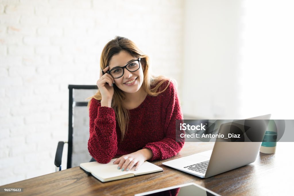 Beautiful female writer Portrait of beautiful caucasian woman writing a book at her desk with laptop 20-29 Years Stock Photo