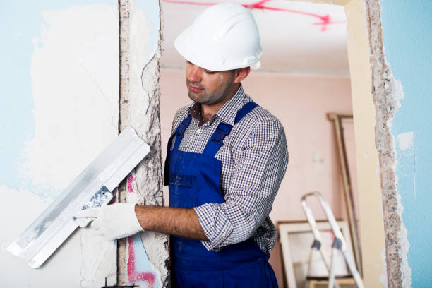 istock Repairman in helmet plastering wall with putty 965723434