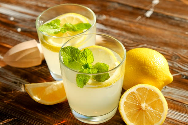 istock Rustic composition with freshly squeezed homemade cold lemonade in bottle and glasses with condensation droplets. 965723810
