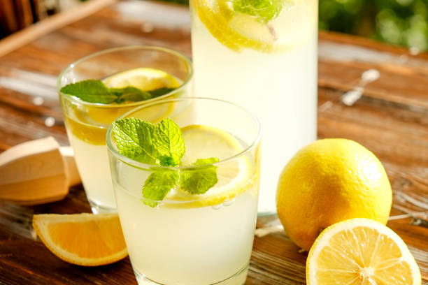 istock Rustic composition with freshly squeezed homemade cold lemonade in bottle and glasses with condensation droplets. 965723936