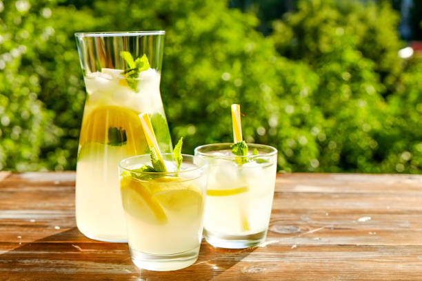 istock Rustic composition with freshly squeezed homemade cold lemonade in bottle and glasses with condensation droplets. 965724046