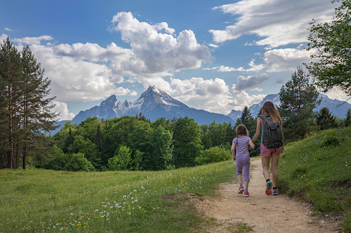 Mother and daughter hiking on a gravel path in themountains. Watzmann mountain in the background