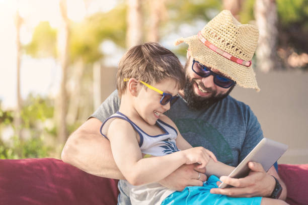 istock Father and son at sunset with digital tablet on vacation 965739106