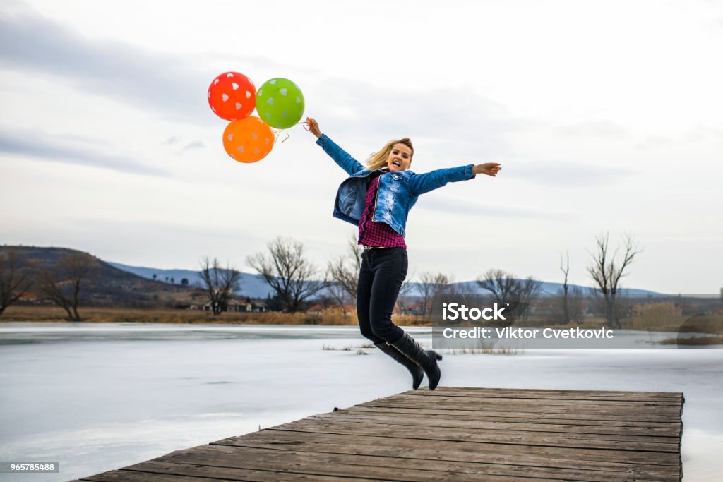 Happy Jumping Happy girl with balloons jumping at dock 18-19 Years Stock Photo