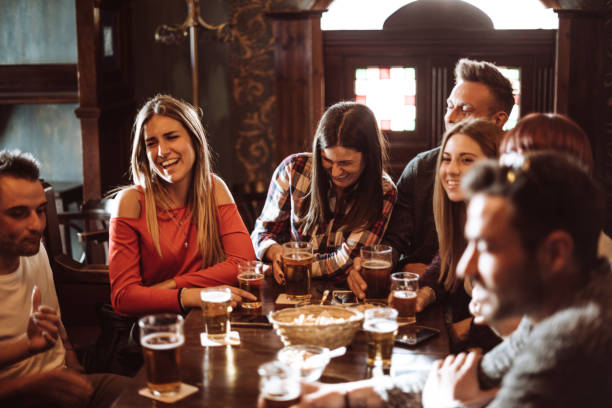persone che parlano al chiuso in un pub con le birre - friendship drinking beer group of people foto e immagini stock