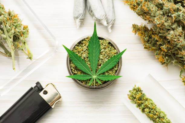 istock weed on a white wooden background, grinder with crushed Joint an use THC and CBD 965834058