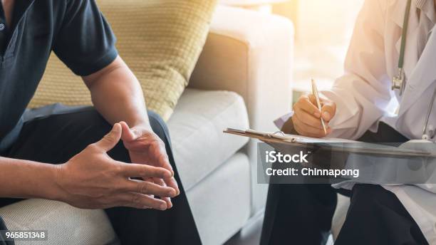 Doctor Consulting Male Patient Working On Diagnostic Examination On Mens Health Disease Or Mental Illness While Writing On Prescription Record Information Document In Clinic Or Hospital Office Stock Photo - Download Image Now