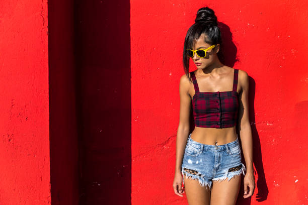 Young woman standing in front of red background.