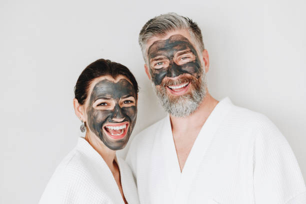 Happy couple wearing a charcoal mask Happy couple wearing a charcoal mask facial mask beauty product stock pictures, royalty-free photos & images