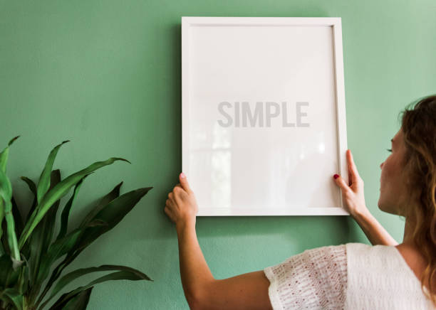 istock Girl hanging a frame on a green wall 965899698