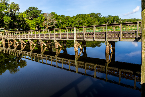 An Interesting Perspective of a Wooden Walkway or Bridge to a Fishing Dock on a Summer Day.  Still waters and nice reflection.