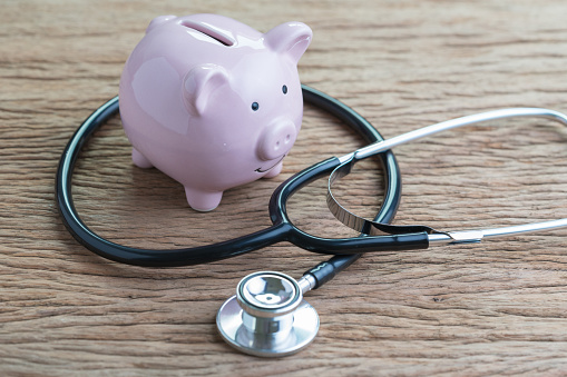 Cuidado de la salud, médicos, honorarios de seguro o financiera salud cheque concepto, estetoscopio con rosa hucha en mesa de madera photo