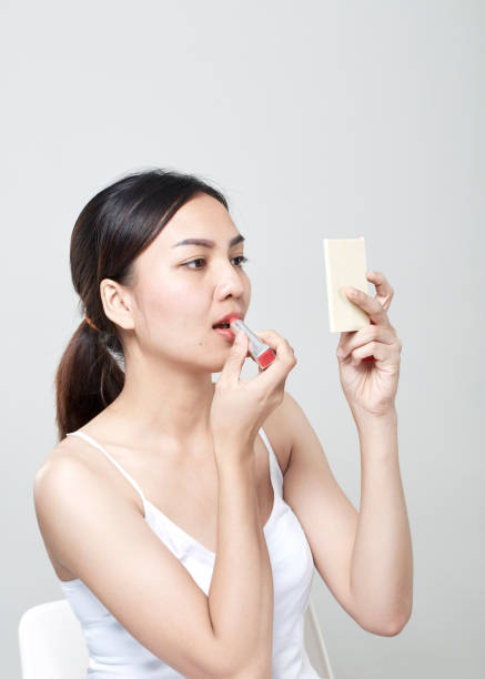 istock asian woman applying lipstick in mirror 965989118