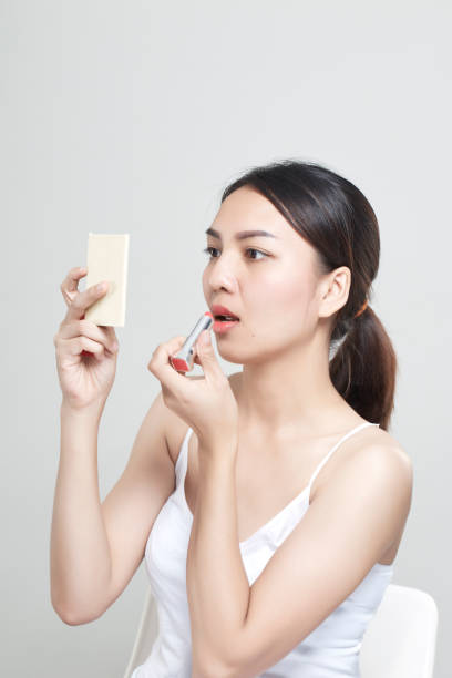 istock caucasian woman applying lipstick in mirror 965989126