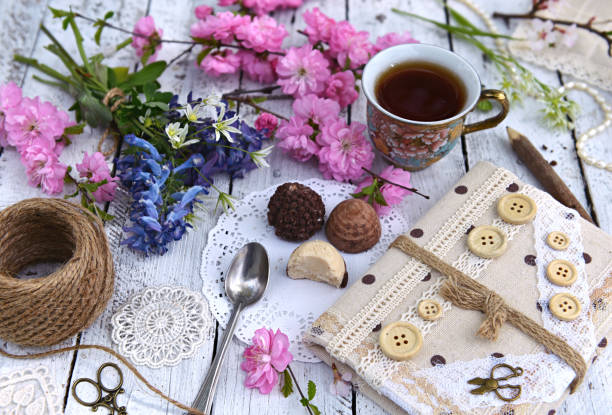 istock Wildflowers, cherry tree branches in blossom, cup of tea and diary on planks 966034834