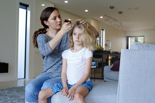 Concerned Mother Doing Head Lice Inspection On Daughter Daughter in Australian House