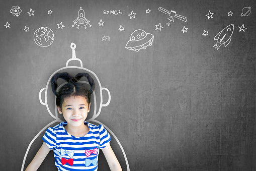 Science technology engineering maths STEM education concept with school girl kid in astronaut helmet and creative innovative knowledge learning doodle on teacher's chalkboard