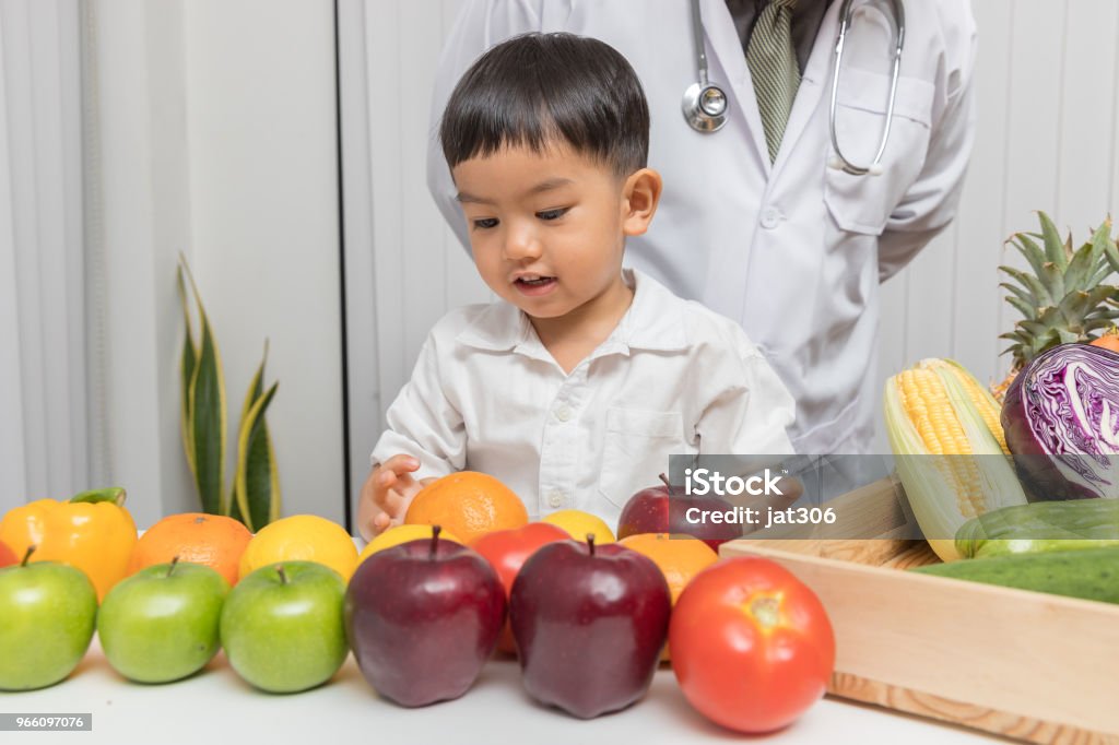 Gesundes und Ernährungskonzept. Kind lernen über Ernährung mit Arzt zu wählen, essen frisches Obst und Gemüse. - Lizenzfrei Abnehmen Stock-Foto