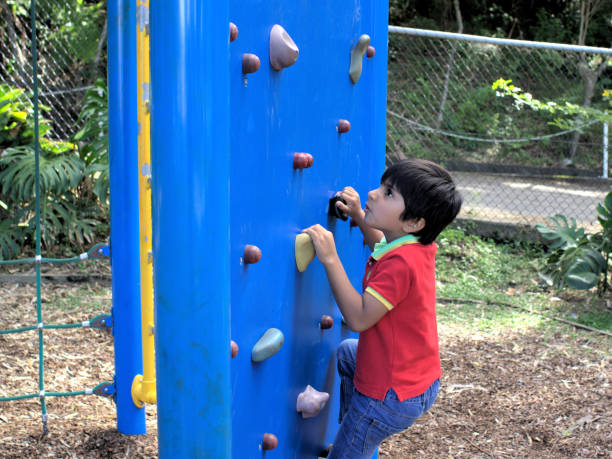 istock Kid going up on climbing wall at park 966113638