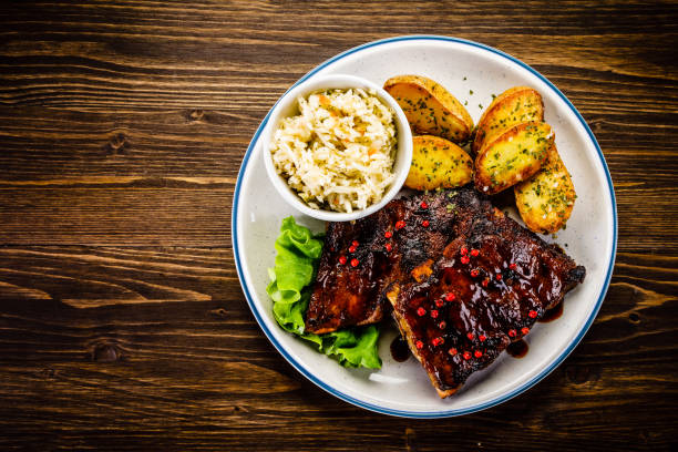 istock Grilled ribs, fried potatoes and vegetables on wooden background 966168062