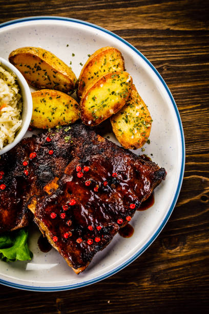 istock Grilled ribs, fried potatoes and vegetables on wooden background 966168130