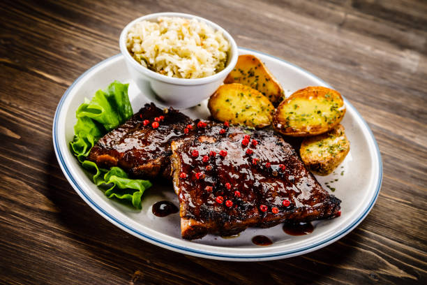 istock Grilled ribs, fried potatoes and vegetables on wooden background 966168366