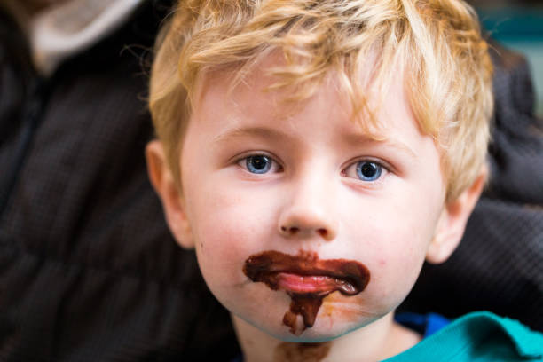 kleiner junge mit schokoladeneis auf gesicht verschmiert - child chocolate ice cream human mouth stock-fotos und bilder