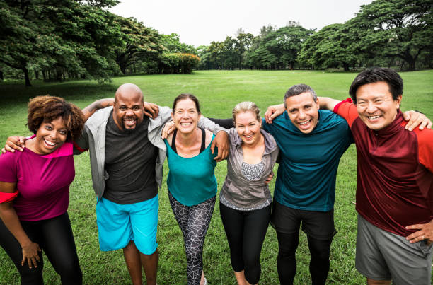 Group of cheerful diverse friends in the park Group of cheerful diverse friends in the park arm around stock pictures, royalty-free photos & images