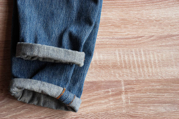 close up of fold selvedge denim jeans on wooden background with copy space for text stock photo