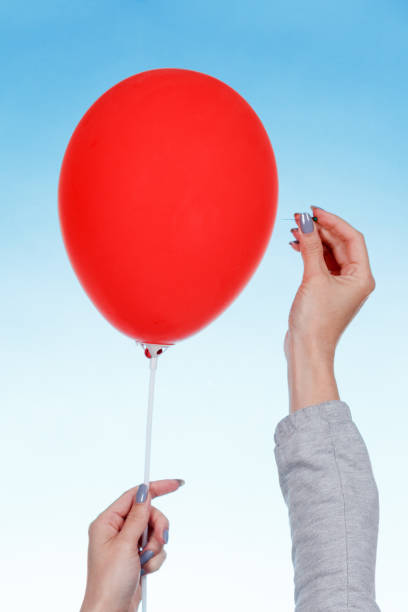 istock hand holding needle near balloon. isolated on white. Danger concept. 966199702
