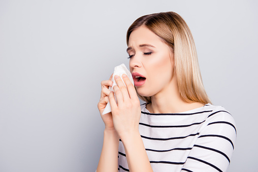 Caucasian woman is shown using a nasal spray in her bedroom to alleviate her congestion. Treatment for Allergies or Common Cold. Woman Using Nasal Spray Drops of Medicine in Her Nose. Rhinitis, Allergy.
