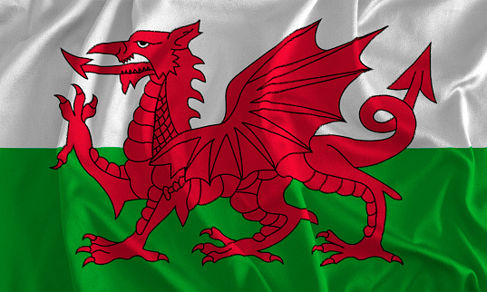 Flag of Wales blowing in the wind. \nFull page Wales flying flag.