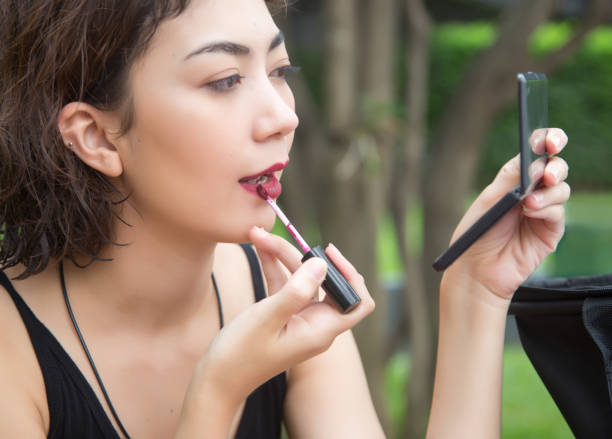 istock beautyful lady use lipstick to make up her face with mirror. 966220106