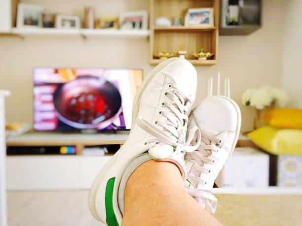 istock Watching cooking recipes on tv. Focus on white shoes 966220690
