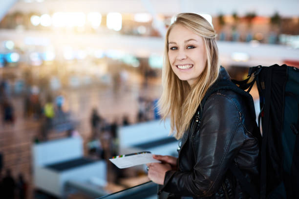 istock Young woman with boarding pass overlooking check-in counters at airport 966223974