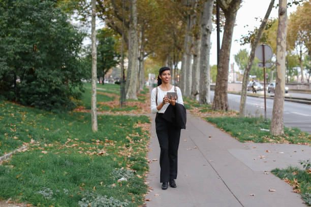 istock Afro american female student walking with tablet in autumn park, wearing backpack 966225948