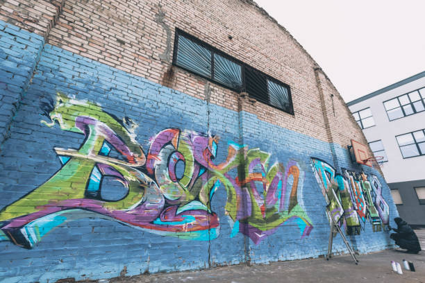 street artist painting colorful graffiti on wall - graffiti men wall street art imagens e fotografias de stock