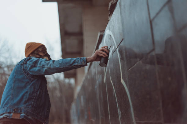 istock man in respirator painting graffiti on building with can 966240220