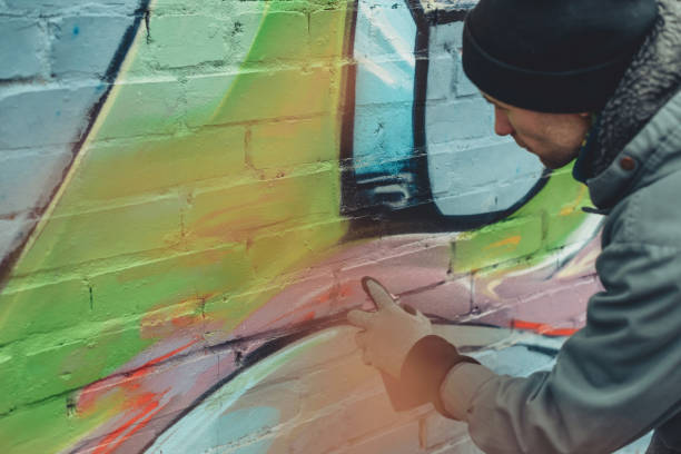 istock man painting colorful graffiti on wall 966242684